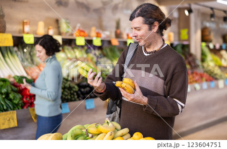 Adult man chooses bananas at vegetable shop 123604751