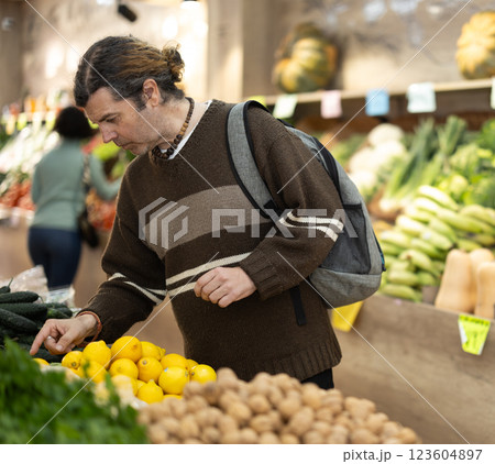 man stands in a supermarket near a stall and looks at vegetables 123604897