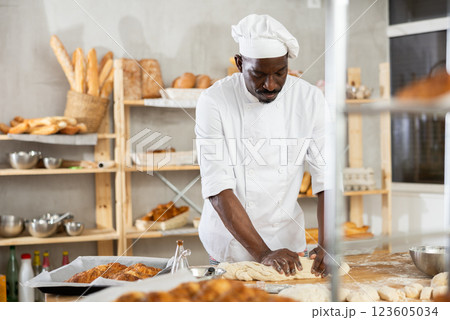 Experienced black baker kneading dough in artisan bakery 123605034