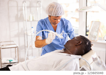 African man undergoes facial skin moisturizing procedure with hydrogen-oxygen hydrating nozzle African man undergoes facial skin moisturizing procedure with hydrogen-oxygen hydrating nozzle 123605040