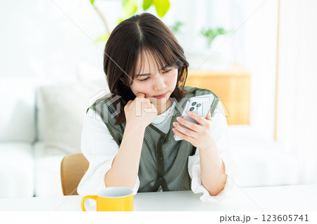 部屋でスマホを操作する若い女性 123605741
