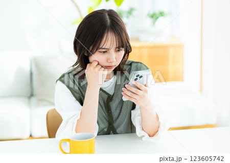 部屋でスマホを操作する若い女性 部屋でスマホを操作する若い女性 123605742