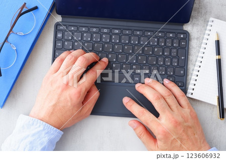 キーボードを接続したタブレット端末でデスクワークをする男性の両手のイメージ キーボードを接続したタブレット端末でデスクワークをする男性の両手のイメージ 123606932