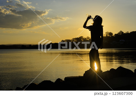 水を飲む女性、夕日とシルエット 水を飲む女性、夕日とシルエット 123607300