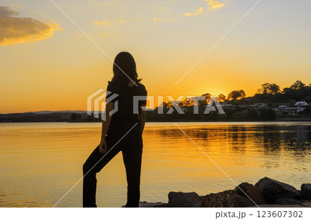夕日を見つめる女性のシルエット 夕日を見つめる女性のシルエット 123607302