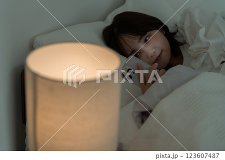 ベッドの中でスマホを操作する若い女性 ベッドの中でスマホを操作する若い女性 123607487