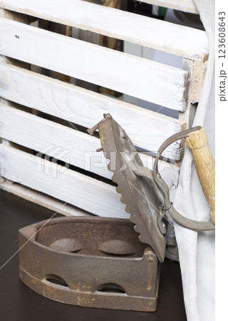 Old iron, heated by hot coals. Opened coal compartment. Standing next to a wooden box and linen cloth. 123608643