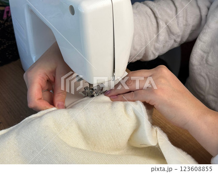 A woman is working at a sewing machine. She is sewing a pet bed from fur fabric. Close-up. Oblique Angle. Close-up. A woman is working at a sewing machine. She is sewing a pet bed from fur fabric. Close-up. Oblique Angle. Close-up. 123608855