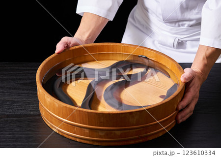 うなぎが入った桶を持つ料理人 123610334
