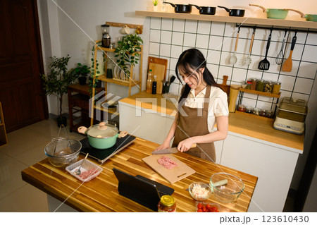 Smiling asian woman preparing ingredients for spaghetti on a wooden counter 123610430