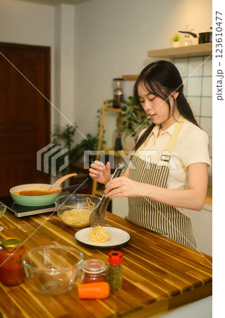 Young woman preparing a homemade pasta dish in a cozy kitchen 123610477