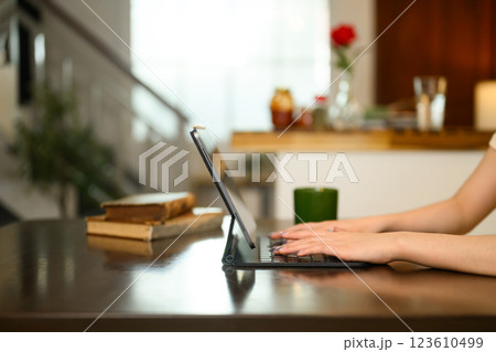 Close up of woman hands typing on digital tablet with a keyboard case on dinning table 123610499