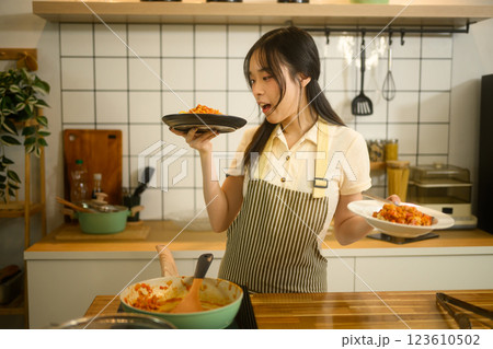 Happy asian woman admires her cooked spaghetti standing in a kitchen 123610502
