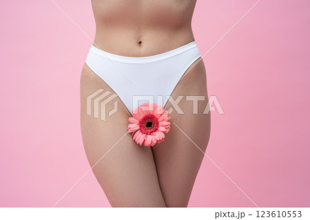 Unrecognizable woman in white panties with gerbera flower standing Unrecognizable woman in white panties with gerbera flower standing 123610553