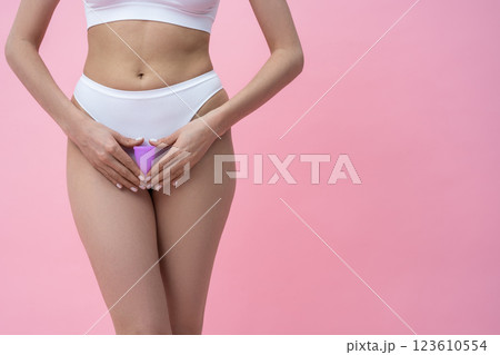 Woman holding hygienic menstrual cup promoting natural feminine care for protection during periods Woman holding hygienic menstrual cup promoting natural feminine care for protection during periods 123610554