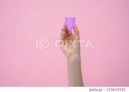 Unrecognizable female hand holding purple silicone menstrual cup 123610585