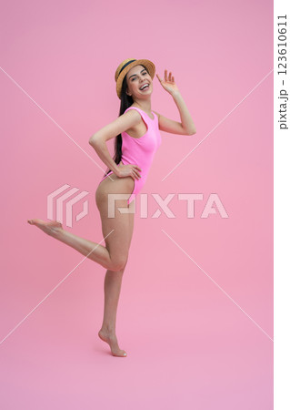 Enjoyed pretty young woman in pink bodysuit and straw hat 123610611