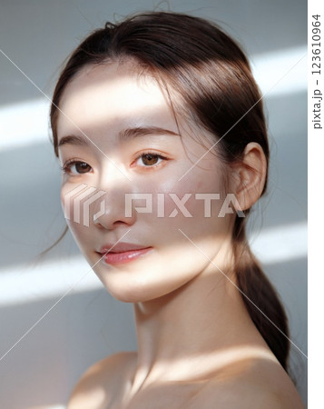 アジア人女性の手入れの行き届いた透明感のある肌と顔のクローズアップ 123610964