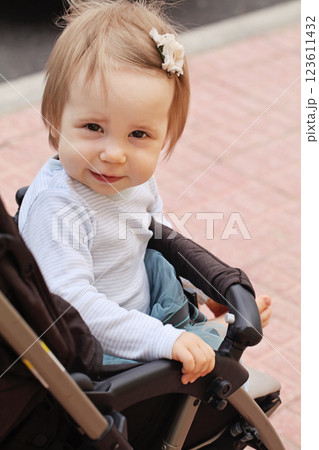 Beautiful little smiling baby girl sitting in pram, outdoors summer portrait 123611432