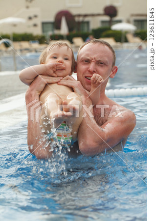 Cute little baby girl having fun with father in swimming pool outdoors 123611645