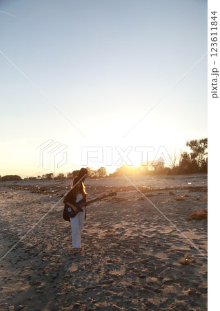 Girl Walks And Plays The Bass Instrument On The Beach Near The Ocean At Sunset Girl Walks And Plays The Bass Instrument On The Beach Near The Ocean At Sunset 123611844