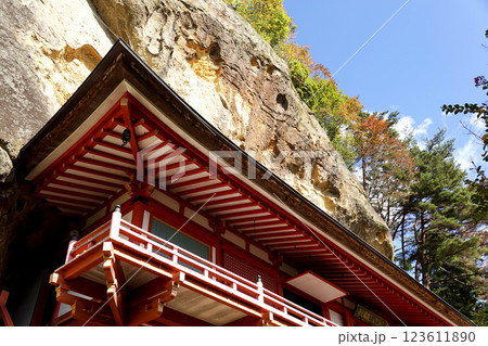 崖下の岩屋に建つ達谷窟毘沙門堂と崖上の紅葉 123611890