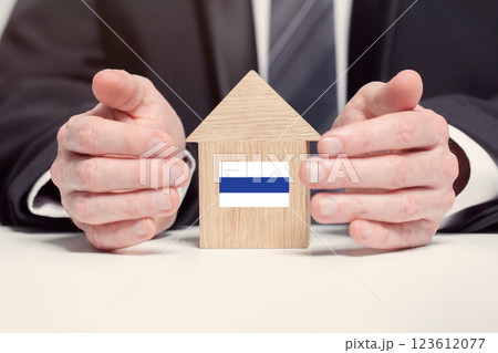 Businessman hand holding wooden home model with Russian flag. insurance and property concepts Businessman hand holding wooden home model with Russian flag. insurance and property concepts 123612077