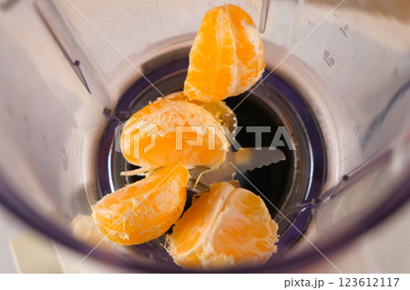 Tangerine pieces falling into blender to cook filling for pie on kitchen. 123612117