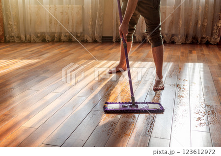 Man mops a dirty wooden floor. Man doing housework at home. Mopping the floor 123612972