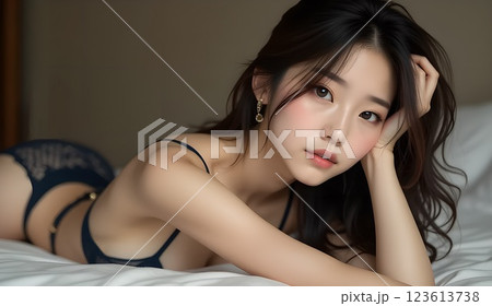 紺色のレースの下着を着た女性がベッドにうつ伏せになり肘を付いている 123613738