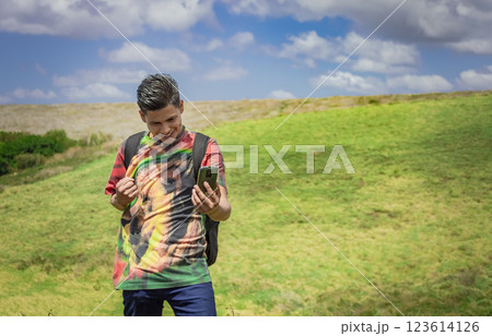 cheerful guy taking a photo in the field, young man taking photos in the field with his cell phone 123614126