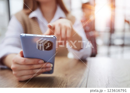 Cheerful student woman sitting at table break holding mobile phone surfing internet Cheerful student woman sitting at table break holding mobile phone surfing internet 123616791