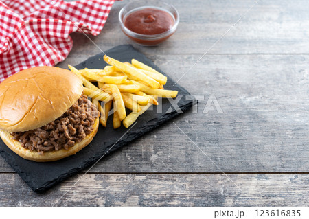 Traditional sloppy joe sandwich with french fries on wooden table and black background Traditional sloppy joe sandwich with french fries on wooden table and black background 123616835