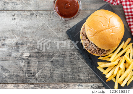 Traditional sloppy joe sandwich with french fries on wooden table and black background Traditional sloppy joe sandwich with french fries on wooden table and black background 123616837