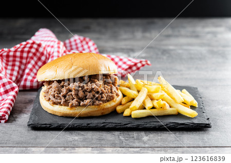 Traditional sloppy joe sandwich with french fries on wooden table and black background Traditional sloppy joe sandwich with french fries on wooden table and black background 123616839