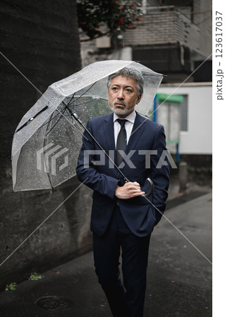 雨の中、傘をさす男性 123617037