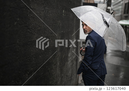 雨の中、傘をさす男性 123617040