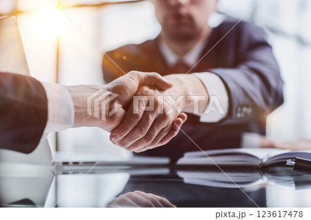 Close-up high-angle view of unrecognizable business men handshaking after close deal and signed agreement at office over table paper contract. 123617478
