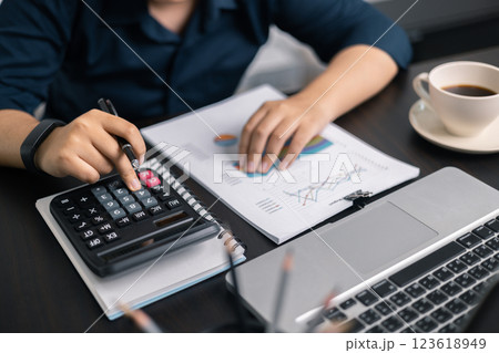 Finance bank tax expense accounting budget money businessman hand use calculator Financial calculate accountant close up calculator with graph chart write office desk Business expense analysis saving 123618949