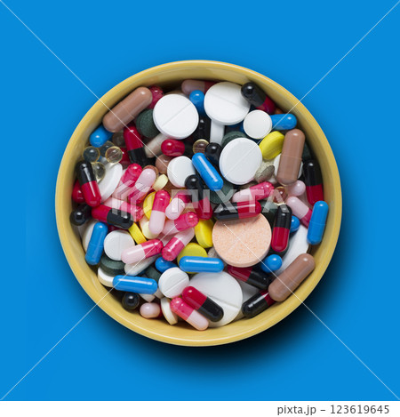 Pile of pills in a bowl on a blue background 123619645
