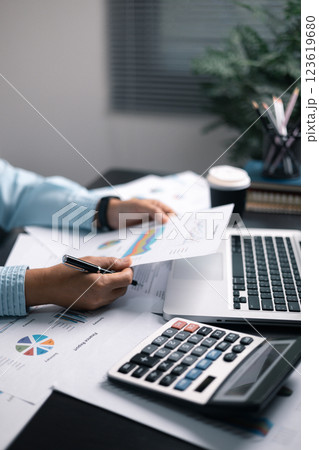 Finance bank tax expense accounting budget money businessman hand use calculator Financial calculate accountant close up calculator with graph chart write office desk Business expense analysis saving 123619680