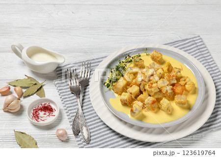 pollock cubes poached in cream saffron sauce pollock cubes poached in cream saffron sauce 123619764