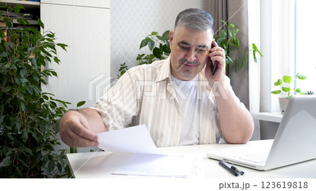 Man Smiling While Talking on Phone at Desk Man Smiling While Talking on Phone at Desk 123619818