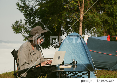 Young business man working computer on peak hill. Hiker online shopping on laptop at sunset, sunrise on top mountain, freelance person remote work with digital tablet. travel vacation holiday concept 123620387