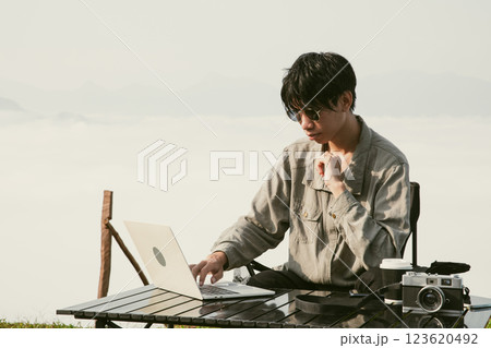 Young business man working computer on peak hill. Hiker online shopping on laptop at sunset, sunrise on top mountain, freelance person remote work with digital tablet. travel vacation holiday concept 123620492