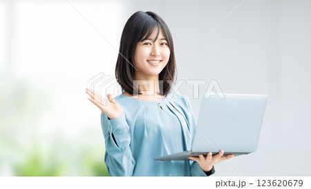 ノートパソコンを持って案内をする笑顔の女性・ビジネスウーマン 123620679
