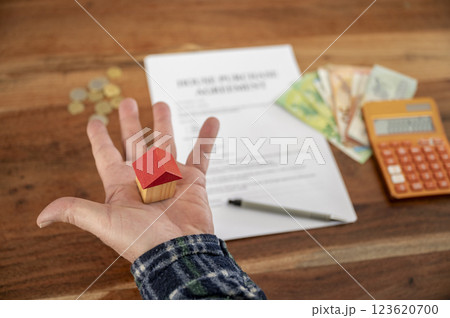 Conceptual image of home ownerhip with a small house model in male hand 123620700