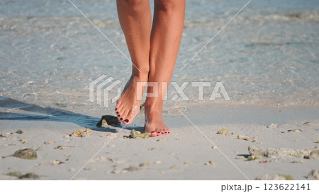 Carefree woman strolls barefoot on a white sand beach, enjoying a sunny summer day by the turquoise ocean Carefree woman strolls barefoot on a white sand beach, enjoying a sunny summer day by the turquoise ocean 123622141