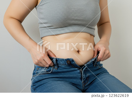 ジーンズが入らなくなった女性のお腹のクローズアップ（AI生成画像） 123622619