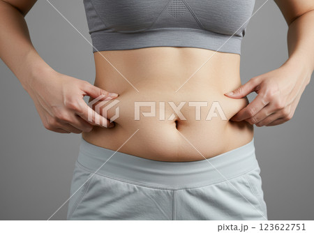 スポーツブラとレギンスを着用してお腹の脂肪をつまむ女性のクローズアップ(AI生成画像) スポーツブラとレギンスを着用してお腹の脂肪をつまむ女性のクローズアップ(AI生成画像) 123622751